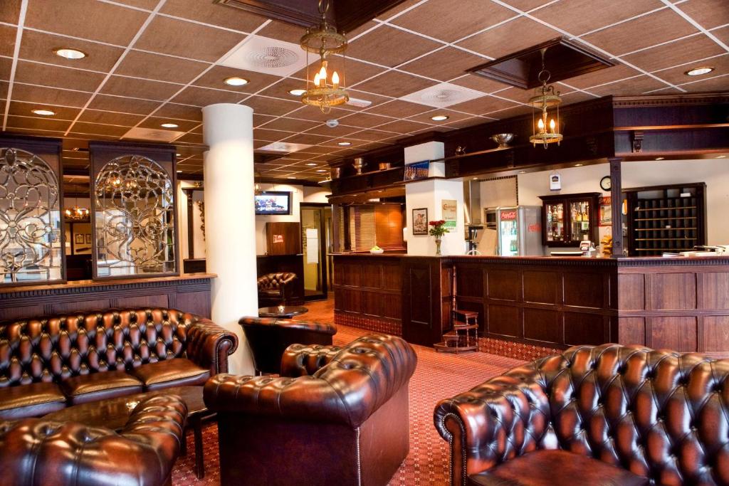 a bar with leather couches and a barber shop at Chesterfield Hotel in Trondheim