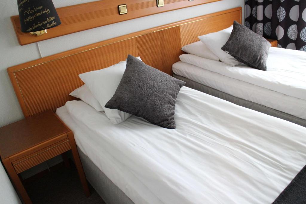 two beds in a hotel room with pillows on them at Arena Hotell in Vänersborg