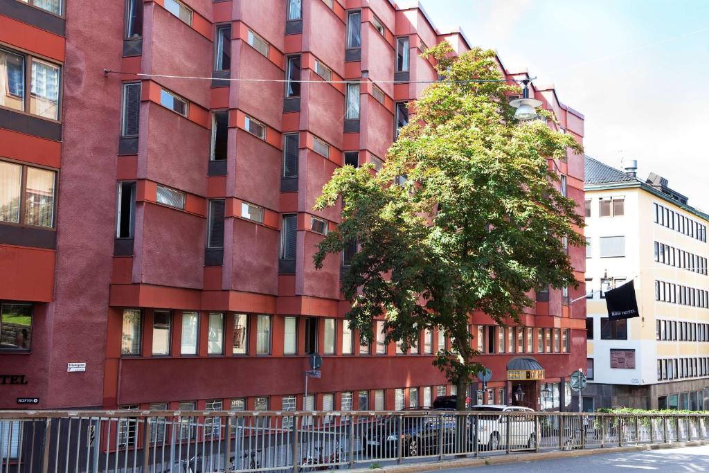 ein rotes Gebäude mit einem Baum davor in der Unterkunft Best Western Kom Hotel Stockholm in Stockholm