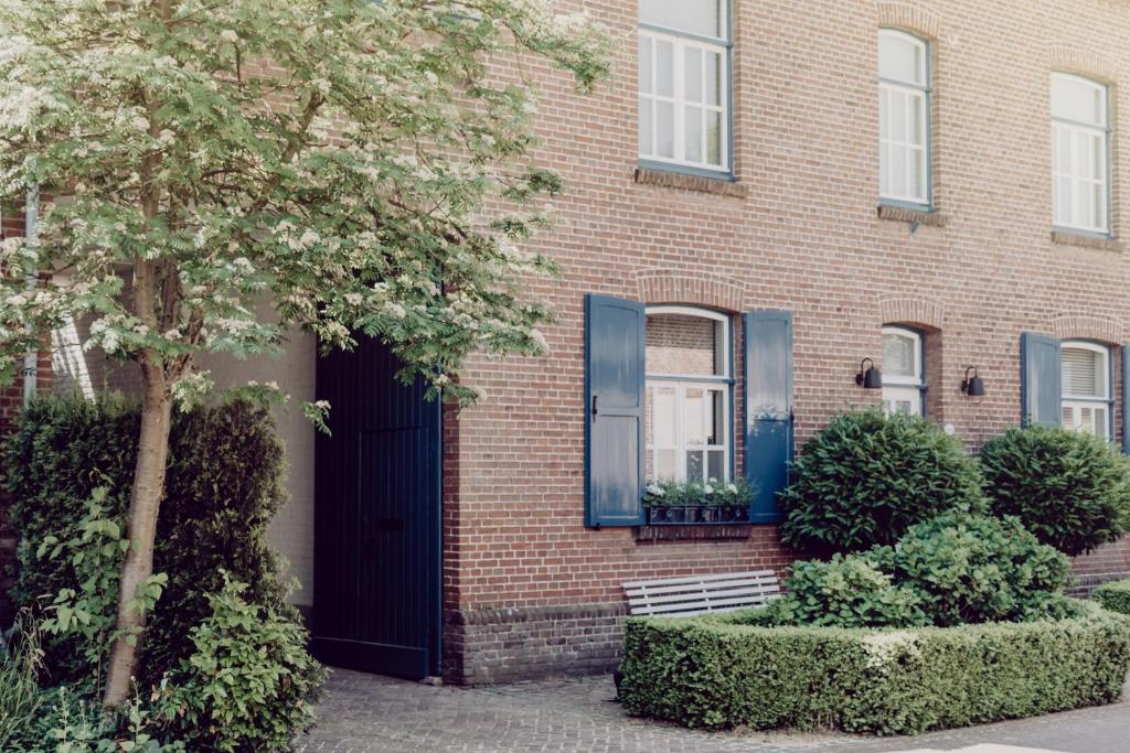 uma casa de tijolos com janelas azuis e uma porta preta em B&B Calidier em Cadier en Keer