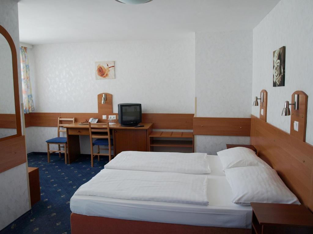 a bedroom with a bed and a desk with a computer at Hotel Terminus in Vienna