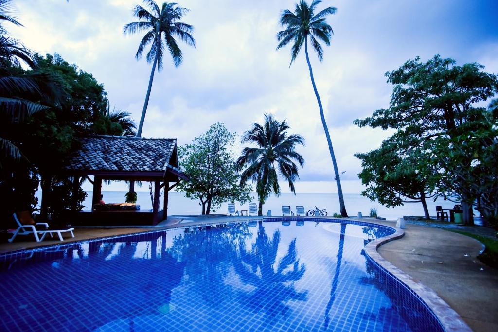 a swimming pool with palm trees in the background at Grand Manita Beach Resort in Lamai