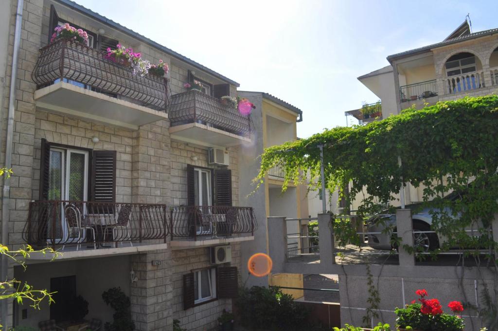 un edificio de apartamentos con balcones, mesas y flores en Apartments Ljubica, en Makarska