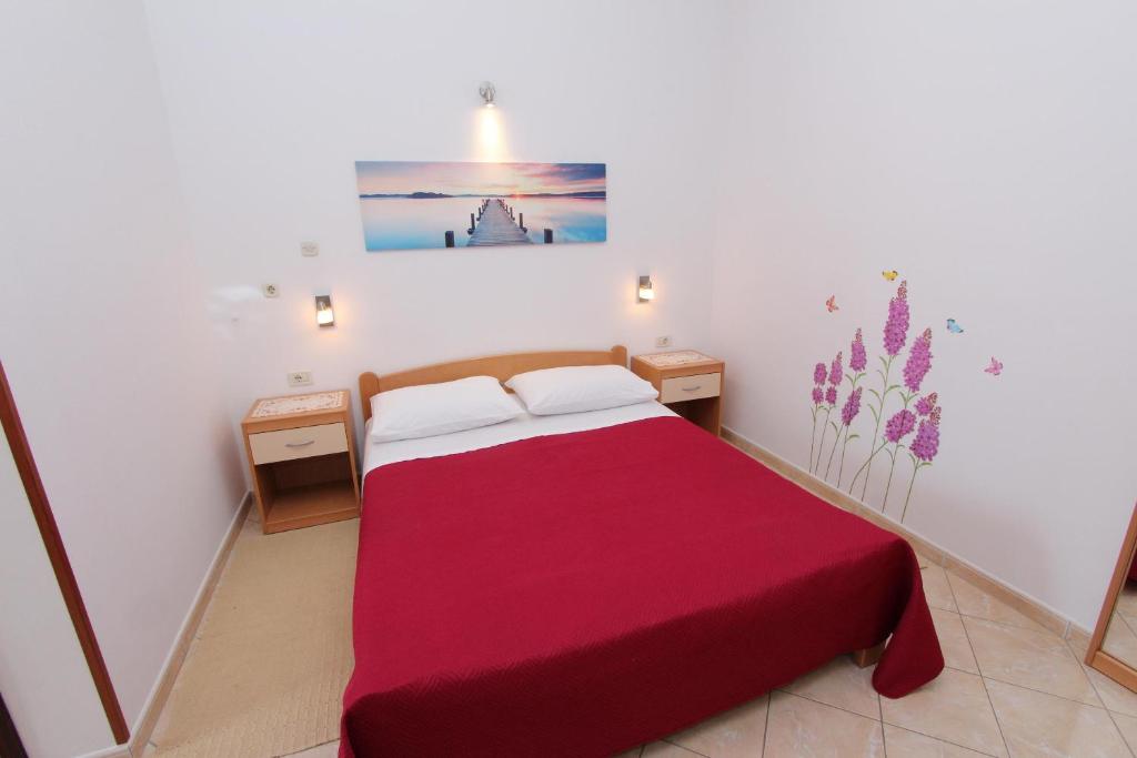 a small bedroom with a red bed with two tables at Room and Apartment Lea in Rovinj
