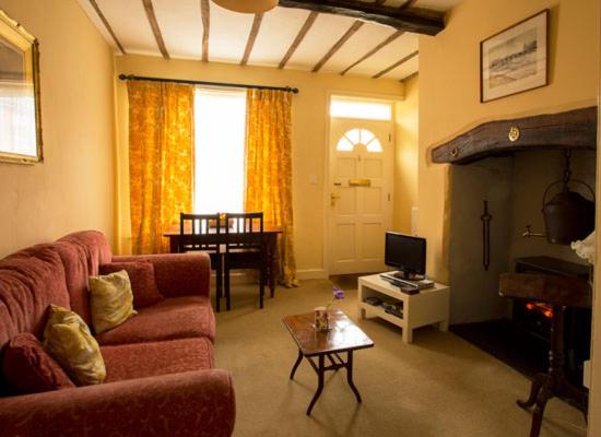 a living room with a couch and a table and a television at Church Lane Cottage in Llanidloes