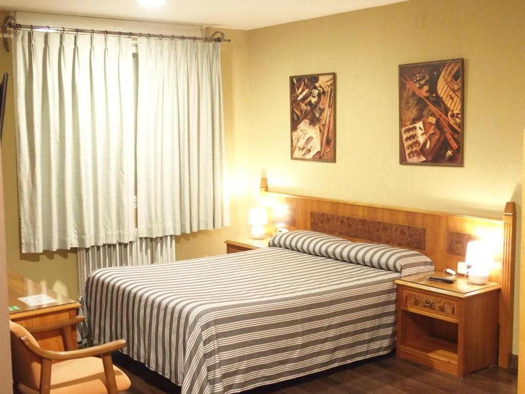 a bedroom with a large bed with a striped blanket at Hotel El Tablazo in Villalba de la Sierra