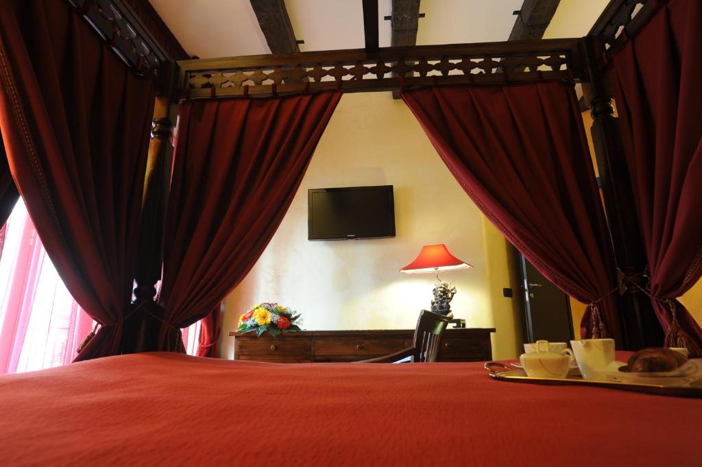 a bedroom with a bed with red curtains and a tv at B&B Muro Torto Cairoli - Struttura sanificata giornalmente con prodotti specifici conformi al Decalogo del Ministero Salute - Personale sottoposto a test sierologico periodicamente in Foggia