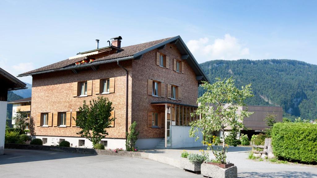 a brick house with a mountain in the background at Appartement Isabella in Bezau