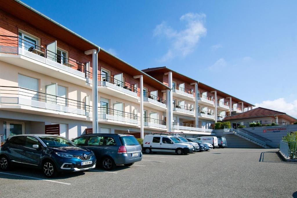 a parking lot with cars parked in front of a building at Séjours & Affaires Genève Gex Les Rives Du Léman in Gex