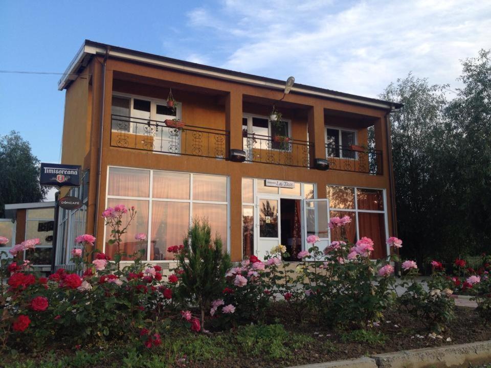 a building with a bunch of flowers in front of it at Pensiunea La Tase in Calafat