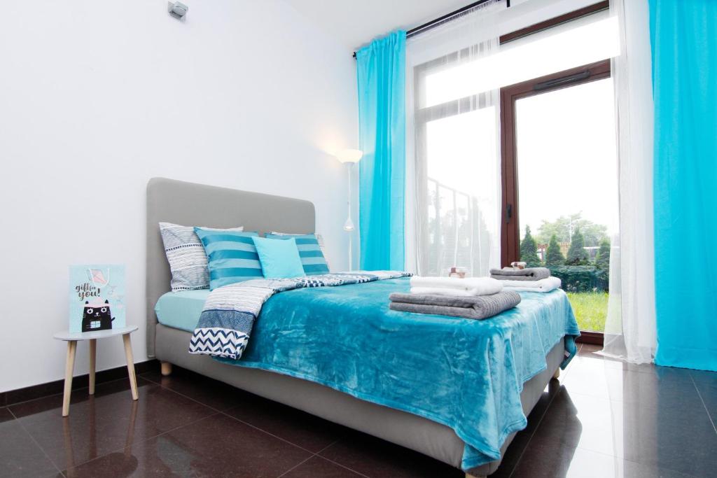 a bedroom with a bed with blue sheets and a window at Blue River - Walonska 7 - Apartment with garden in Wrocław