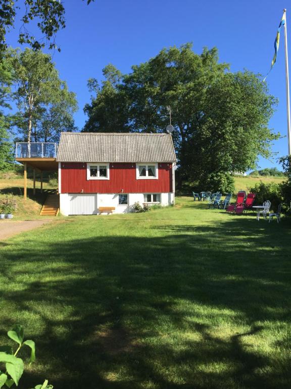 eine rote und weiße Scheune auf einem Grasfeld in der Unterkunft Cottage Båstad/Bjäre in Båstad
