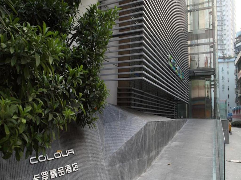 a building with trees on the side of a sidewalk at Shenzhen Dongmen Colour Hotel in Shenzhen