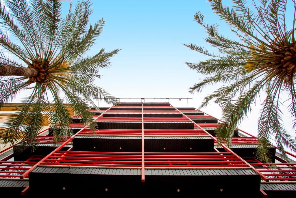 un bâtiment avec des escaliers rouges et deux palmiers dans l'établissement Hotel Borgia, à Gandía
