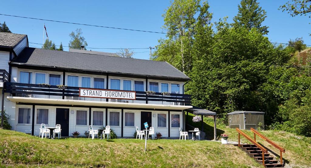 a building with tables and chairs in front of it at Strand Fjordmotel in Ulvik