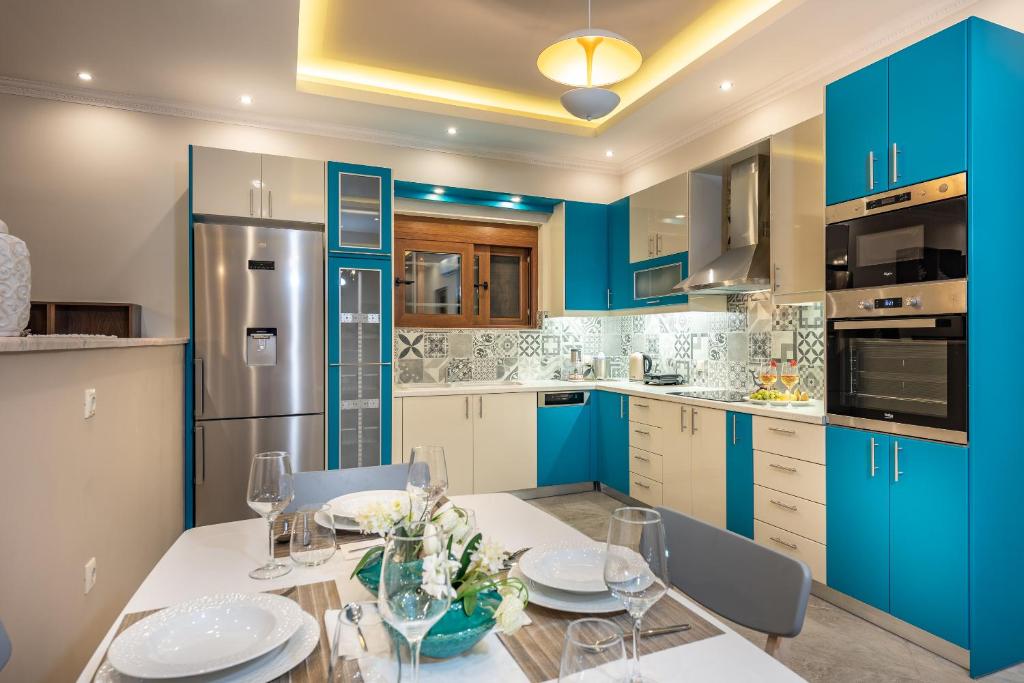 a kitchen with blue cabinets and a table and chairs at Aquarella Luxury Apartment in Argasi