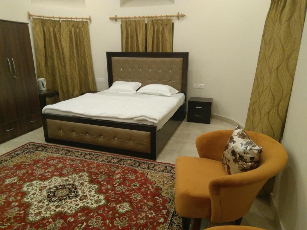 een slaapkamer met een bed, een stoel en een tapijt bij Heritage Homestay in Jammu