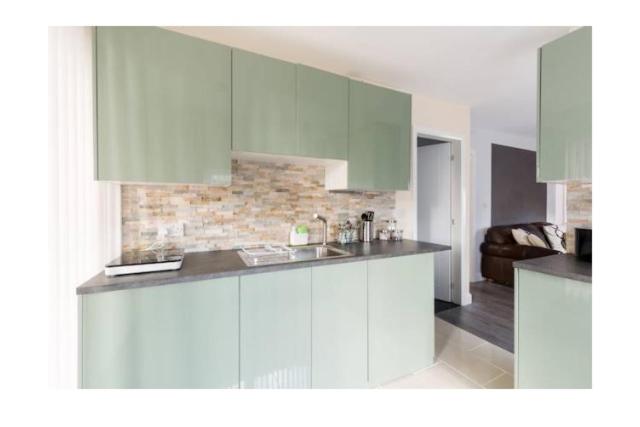 uma cozinha com armários brancos e uma bancada em treetops flat3 Hall Green B28 em Birmingham