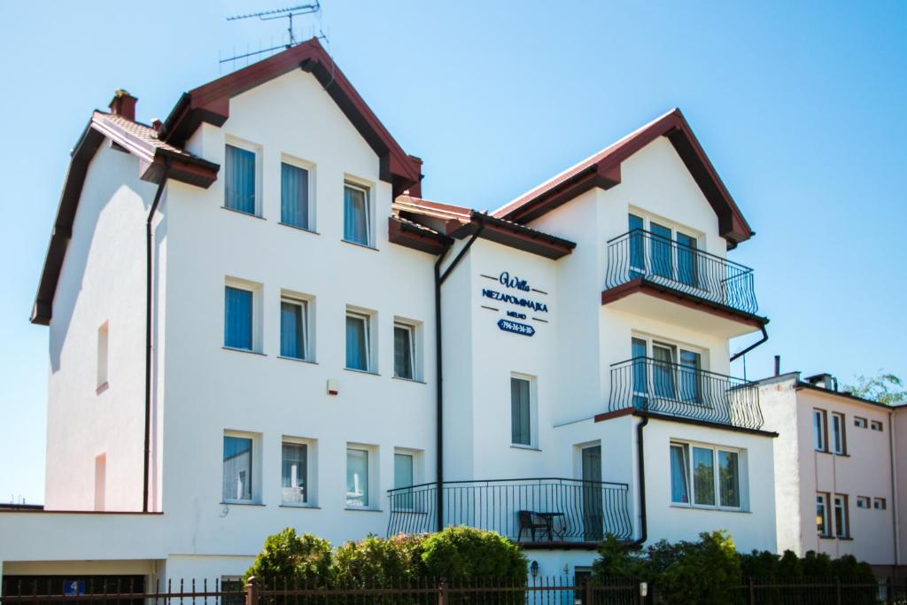 a white building with a sign on it at Willa Niezapominajka Mielno in Mielno