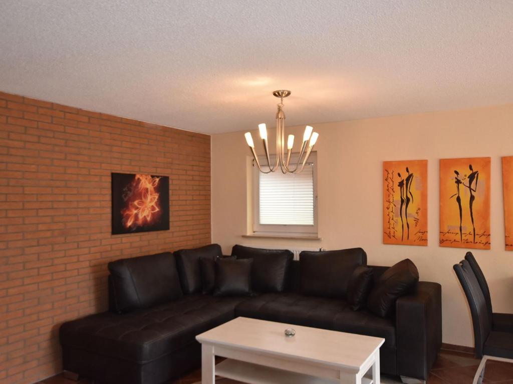 a living room with a black leather couch and a table at Cozy Retreat in Kröpelin in Kröpelin