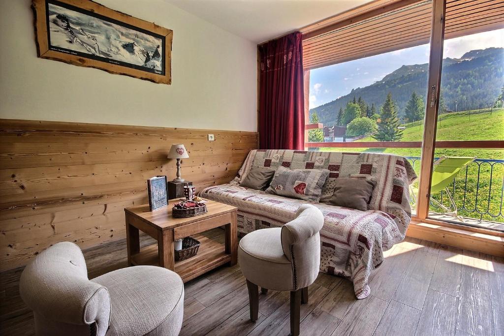 a living room with a couch and chairs and a large window at ARC 1800 Pierra Menta in Arc 1800