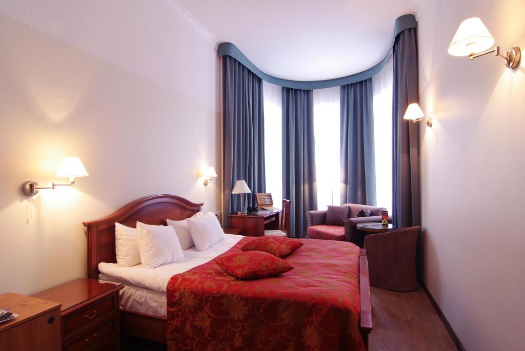 um quarto de hotel com uma cama com um cobertor vermelho em Hotel St. Barbara em Talin