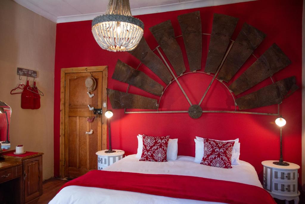 a bedroom with a red wall with a large bed at Mirabel Guesthouse in Parys