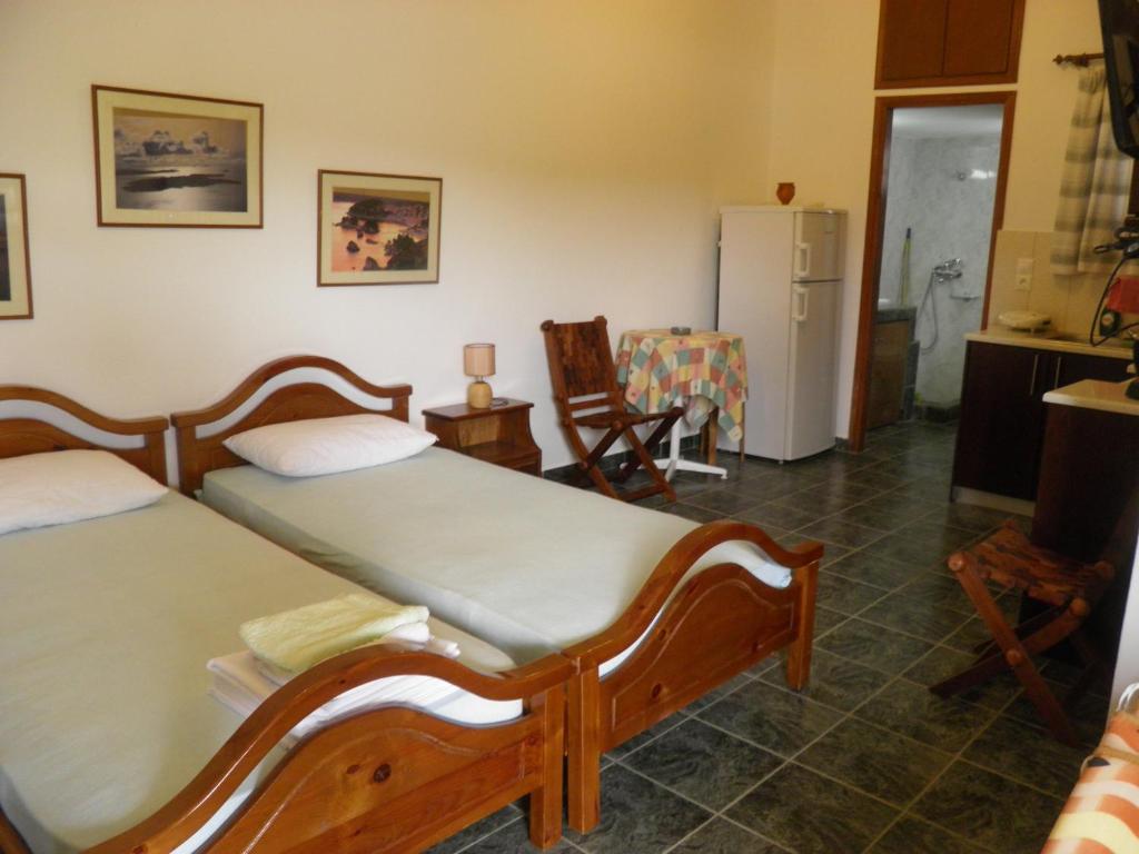 a bedroom with two beds and a kitchen with a refrigerator at Studios Cavo Doro in Otziás