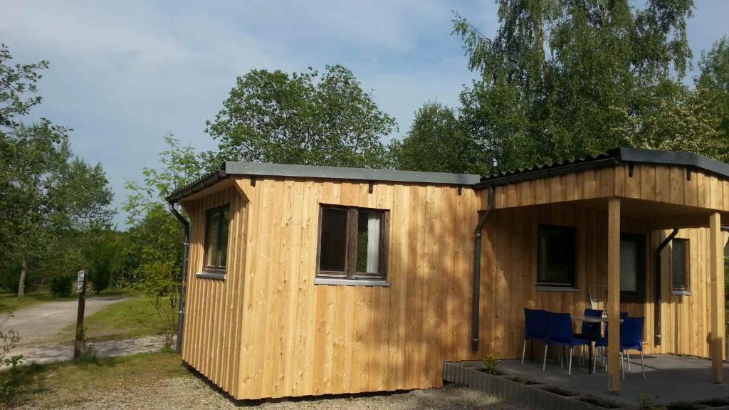 Cabaña de madera pequeña con mesa y sillas en Camping Harfenmühle - Chalet, en Mörschied