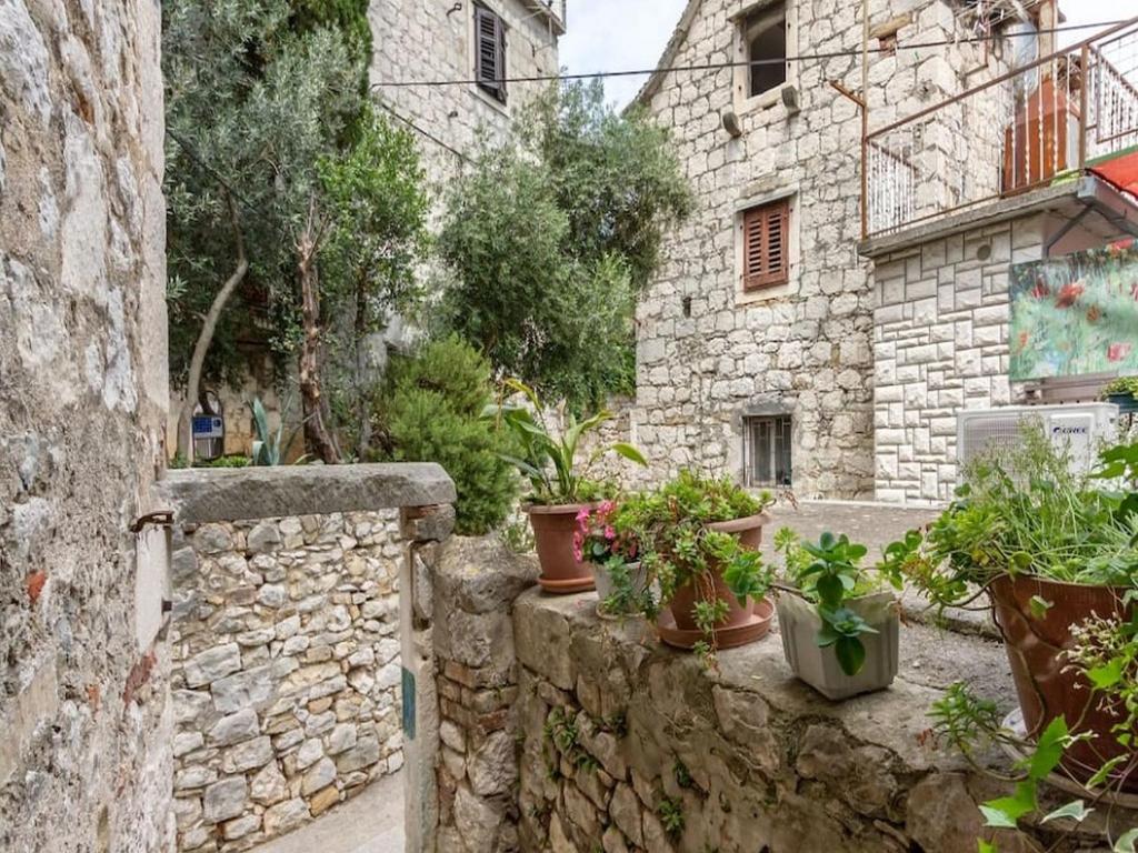 un bâtiment en pierre avec des plantes en pot sur un mur en pierre dans l'établissement Apartment Bova, à Split