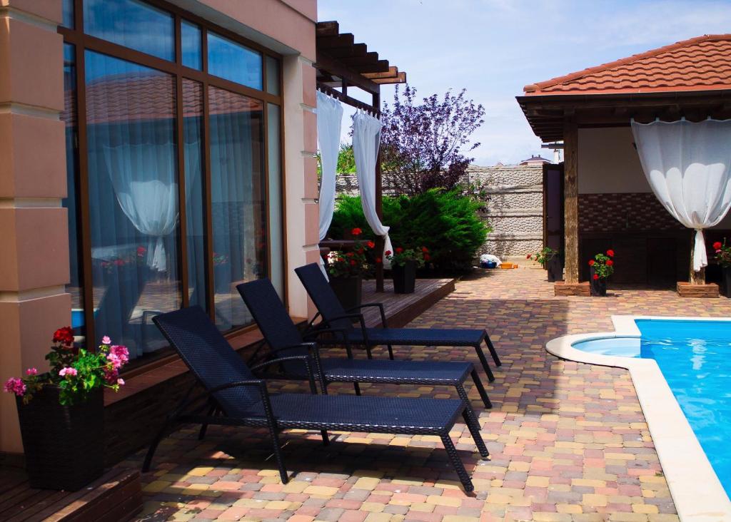 two chairs sitting on a patio next to a swimming pool at Villa Magrib and Shark in Popovka