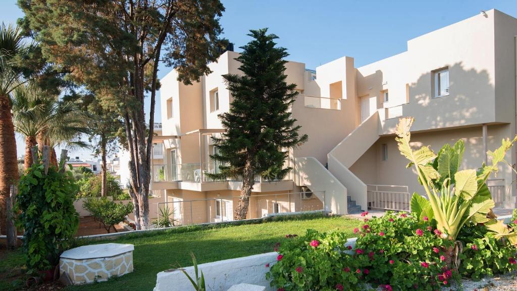 a building with trees and flowers in a yard at Blue Sky Apartments in Malia