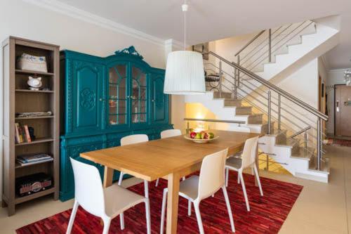a dining room with a wooden table and white chairs at Casa Teresa in Vilamoura