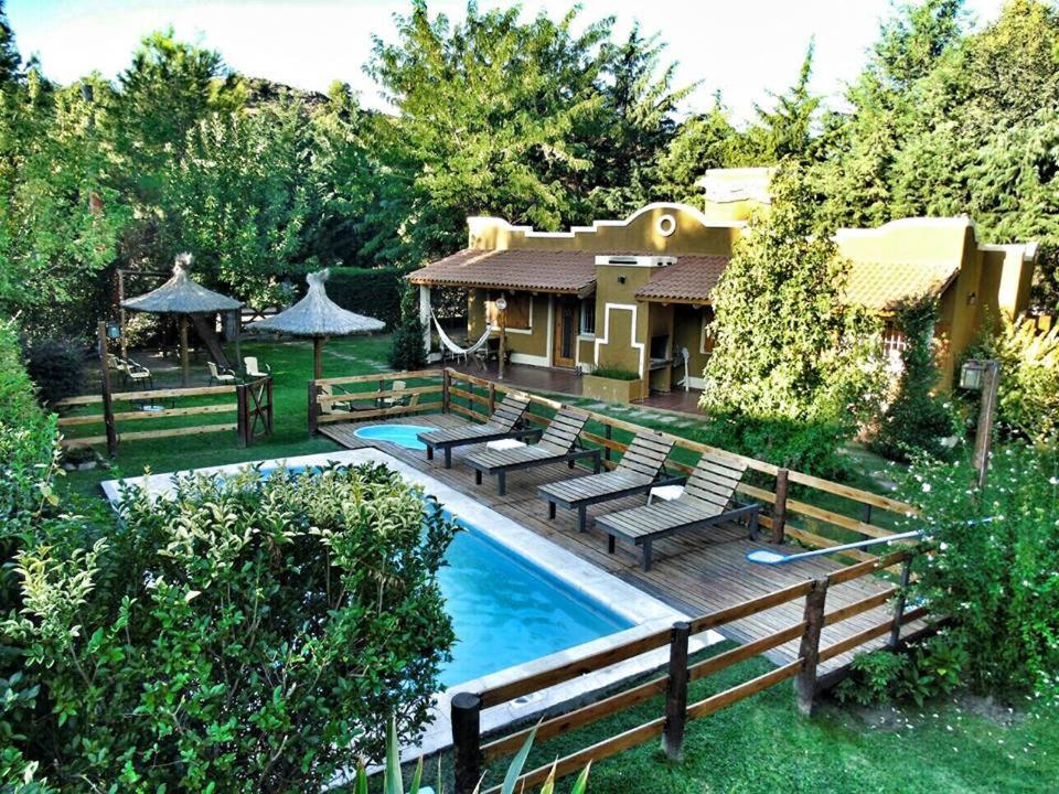 a backyard with a pool with benches and a house at Complejo Retana in Potrero de los Funes