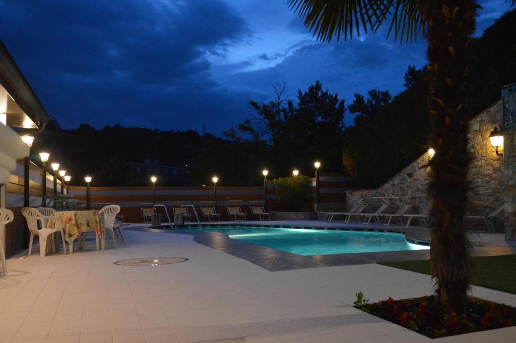 a swimming pool at night with a table and chairs at Hotel Plaza in Tabiano