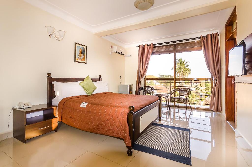 um quarto de hotel com uma cama e uma varanda em Marie's Royale Hotel em Kampala
