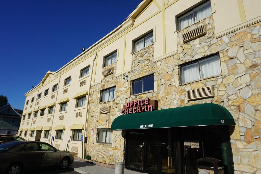 Un edificio con un tendone verde davanti di Floral Park Motor Lodge a Floral Park