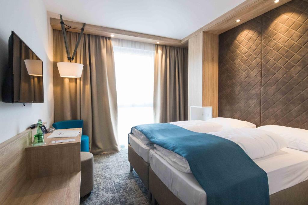 um quarto de hotel com uma cama e uma televisão em Das Alfred em Sankt Pölten