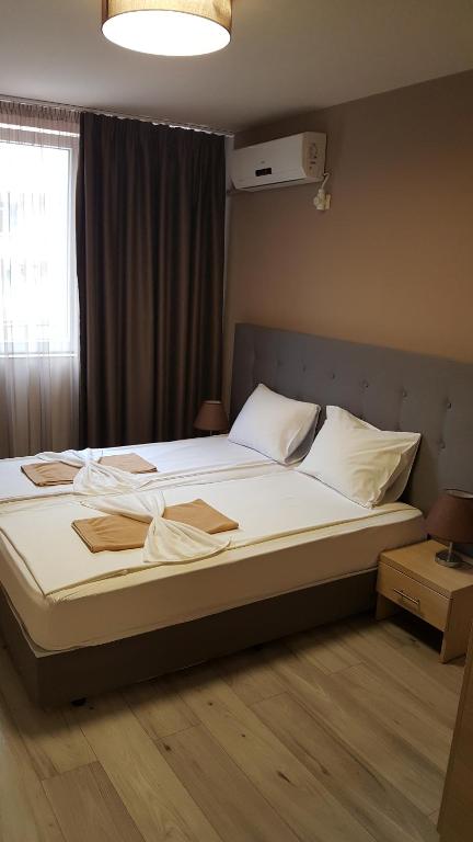 um quarto com uma cama grande com lençóis brancos e uma janela em Sity Sandanski em Sandanski