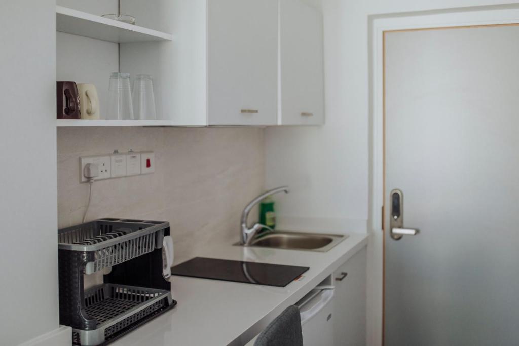 a kitchen with white cabinets and a sink and a dishwasher at River View Boutique Apts in Ayia Napa