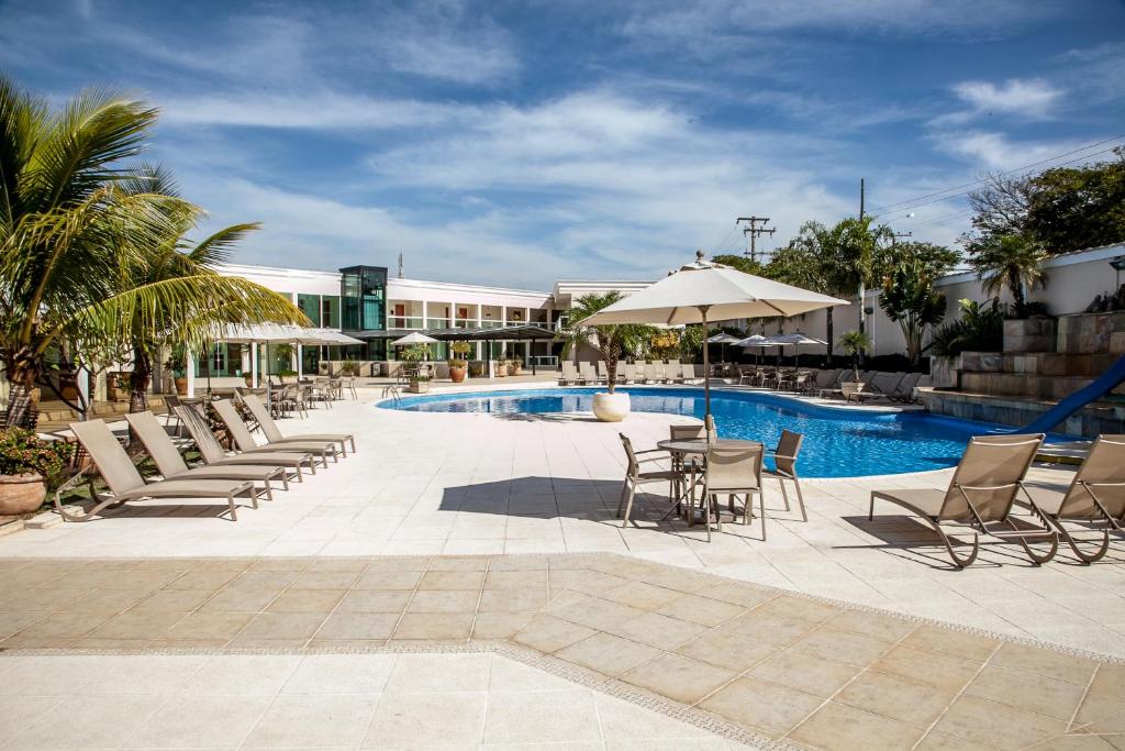 uma piscina com cadeiras, uma mesa e um guarda-sol em Itu Plaza Hotel em Itu