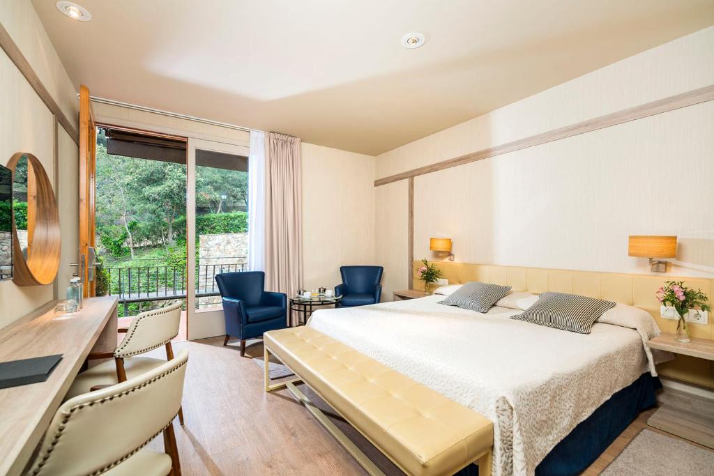 a bedroom with a bed and a desk and chairs at Hotel Santa Marta in Lloret de Mar