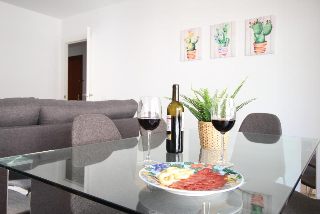 a glass table with a bowl of food and two glasses of wine at Del Parque Flats - Zamarrilla in Málaga