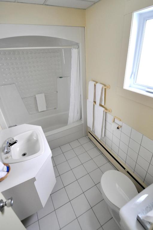 a white bathroom with a sink and a toilet at Auberge le Parasol in Saguenay