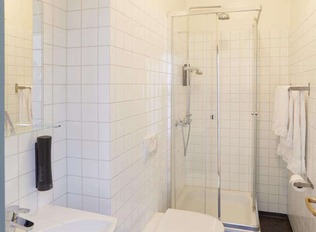 a white bathroom with a shower and a toilet at Fosshotel Eastfjords in Fáskrúðsfjörður