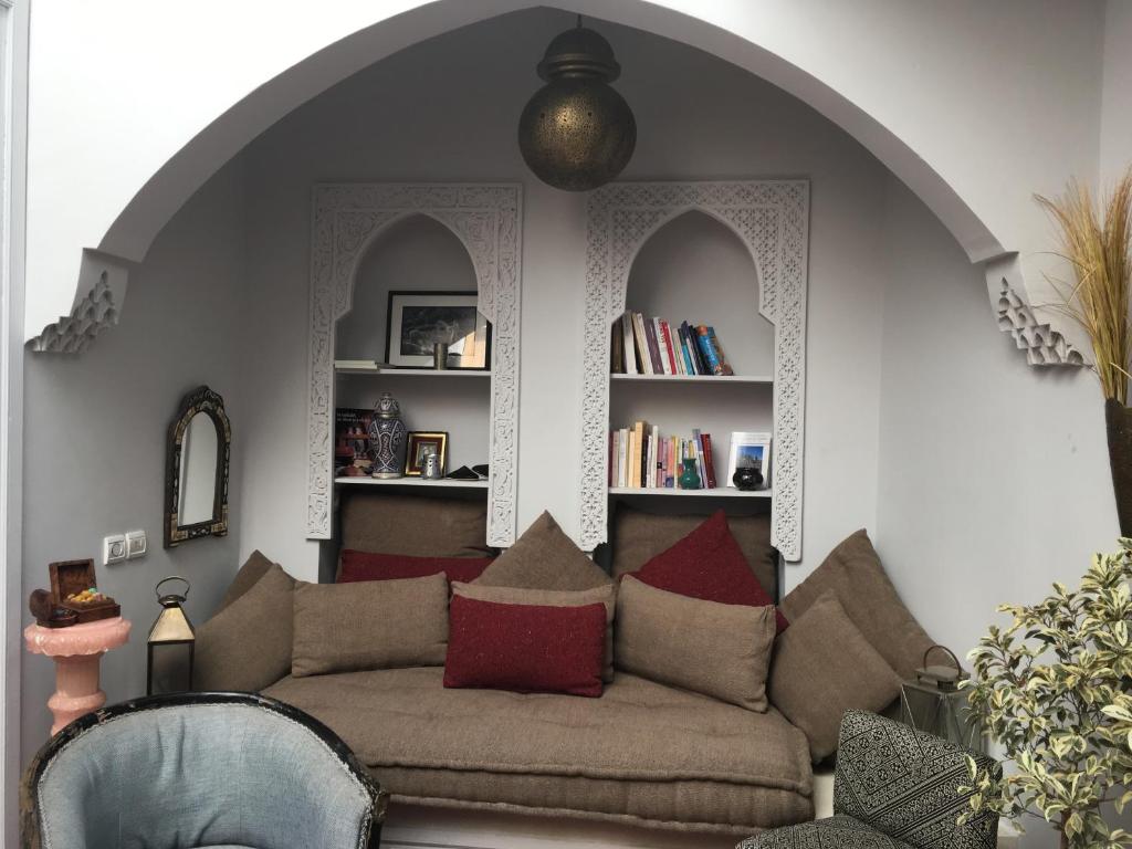 a living room with a couch and shelves with books at Riad Laly Tourisme Eclairé Le bijou de la medina in Marrakesh