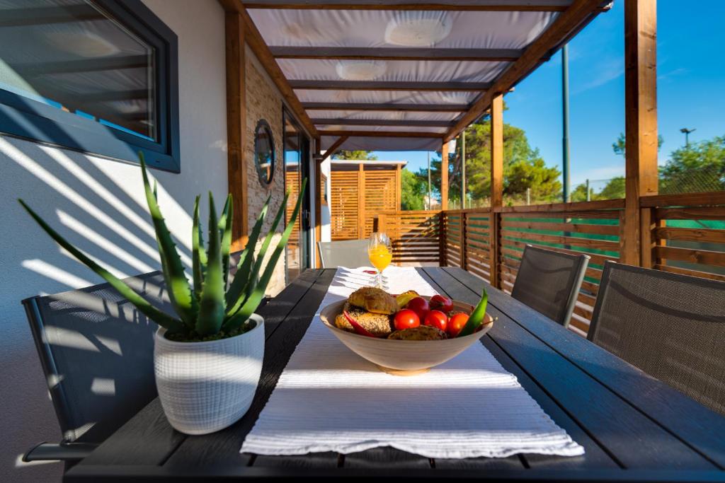 a table with a bowl of fruit and a vase with a plant at Croatia Camp Mobile Homes Vodice in Vodice