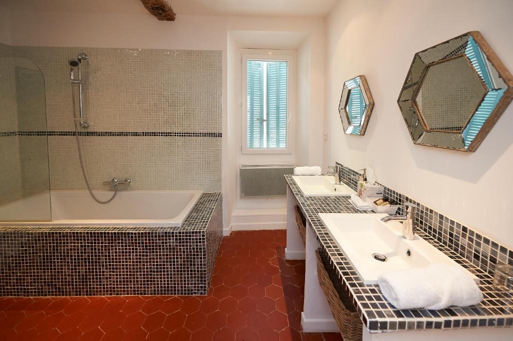 a bathroom with two sinks and a tub and a mirror at La Grande Maison De Nans in Nans-les-Pins