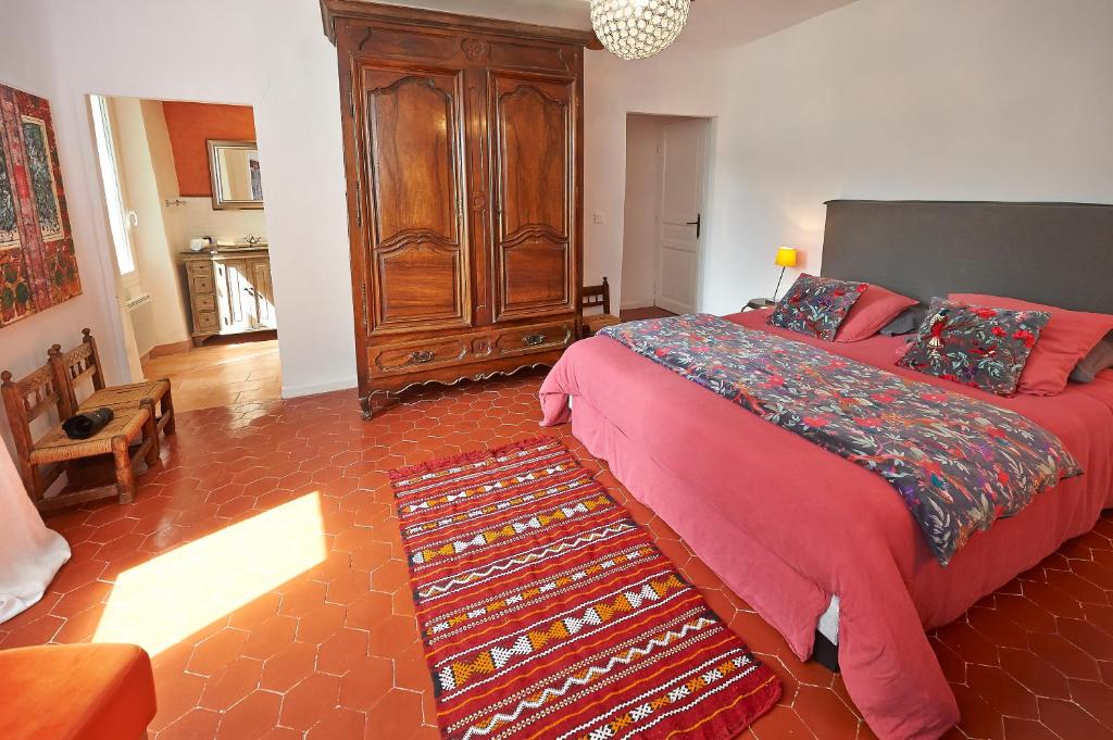a bedroom with a large bed with a red comforter at La Grande Maison De Nans in Nans-les-Pins