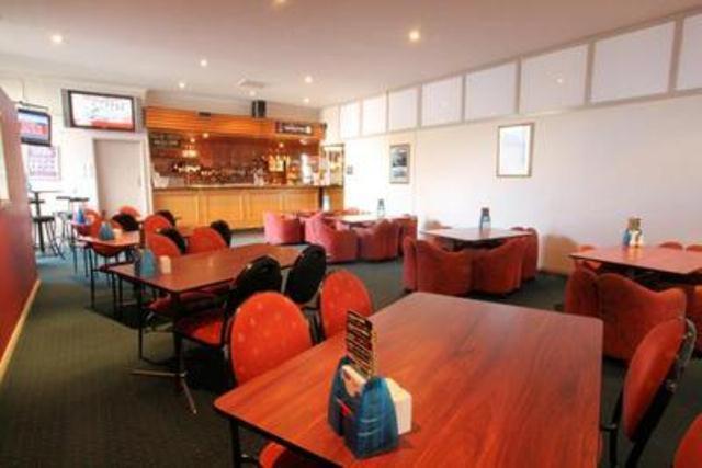 jadalnia ze stołami i czerwonymi krzesłami oraz bar w obiekcie Heemskirk Motor Hotel w mieście Zeehan